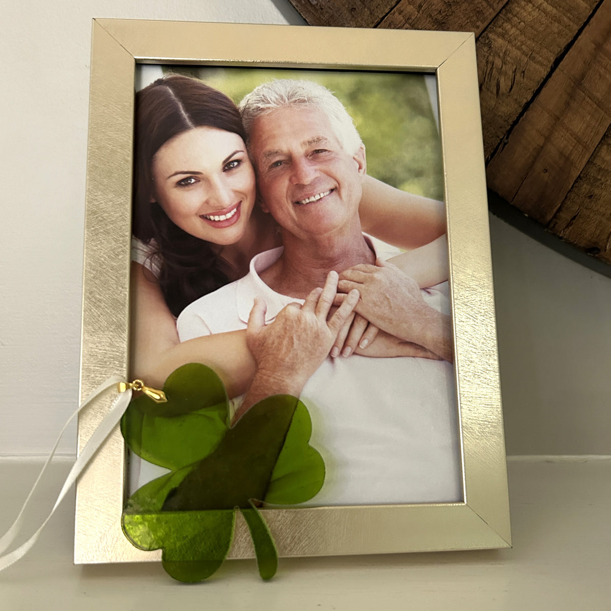 Green glass shamrock leaning against a photo frame.