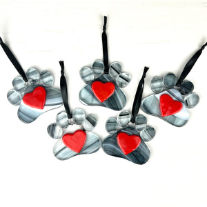 5 of 6:An assortment of glass pawprints, pawprint is a swirl of clear, black, and white with a red heart in the center.