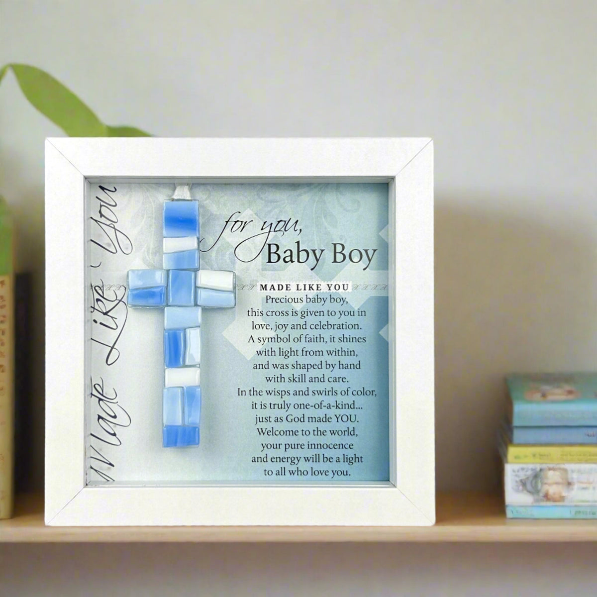 Framed Baby Boy Cross on a nursery bookshelf.