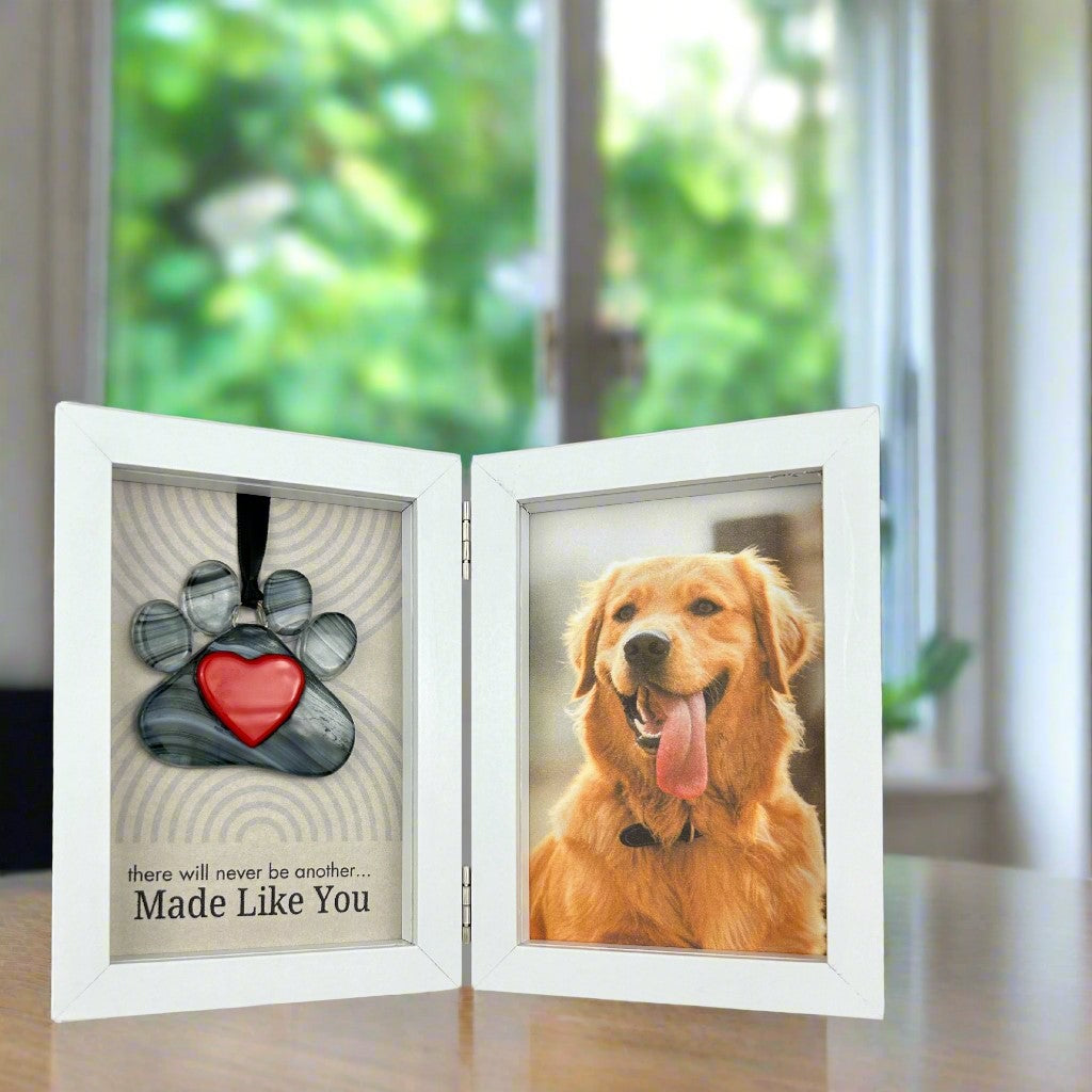 Glass pawprint and photo double frame on a table.