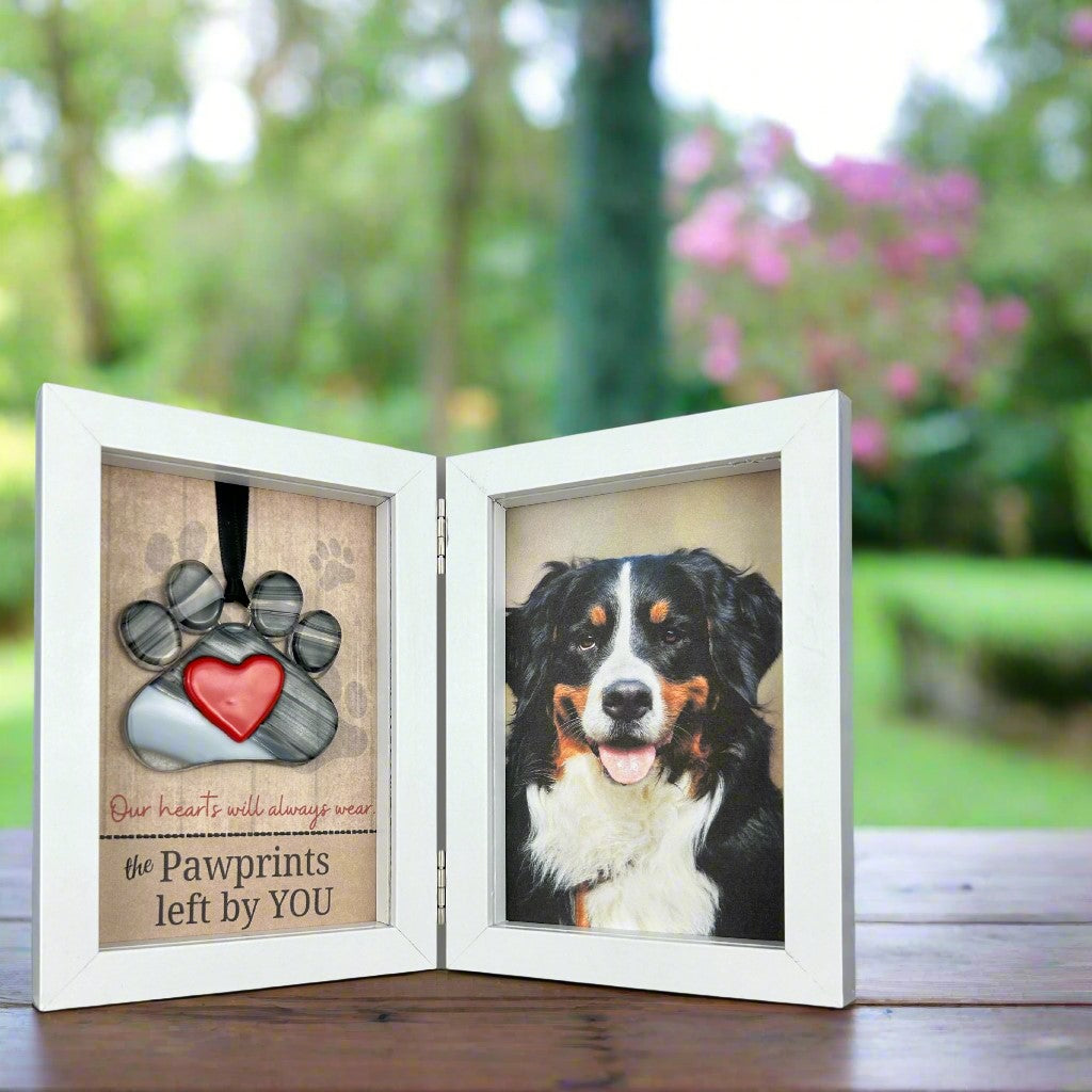 Glass pawprint and photo double frame on a table.