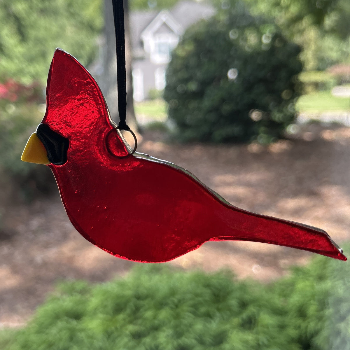 Cardinal ornament hanging in a window.