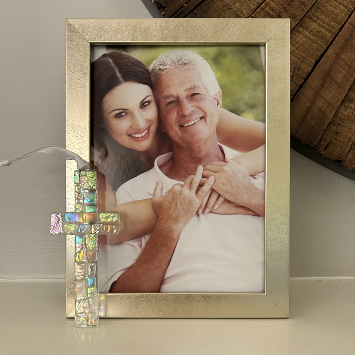 Dichroic glass cross leaning up against a photo of a father and daughter.