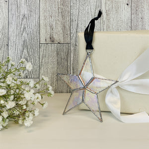 7 of 7:Clear iridescent star with black satin ribbon for hanging.